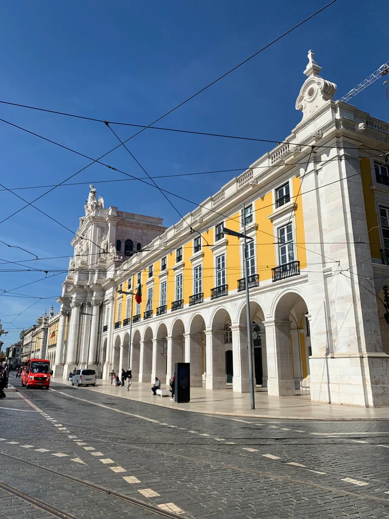 Yellow arcaded buildings and tram wires in central Lisbon